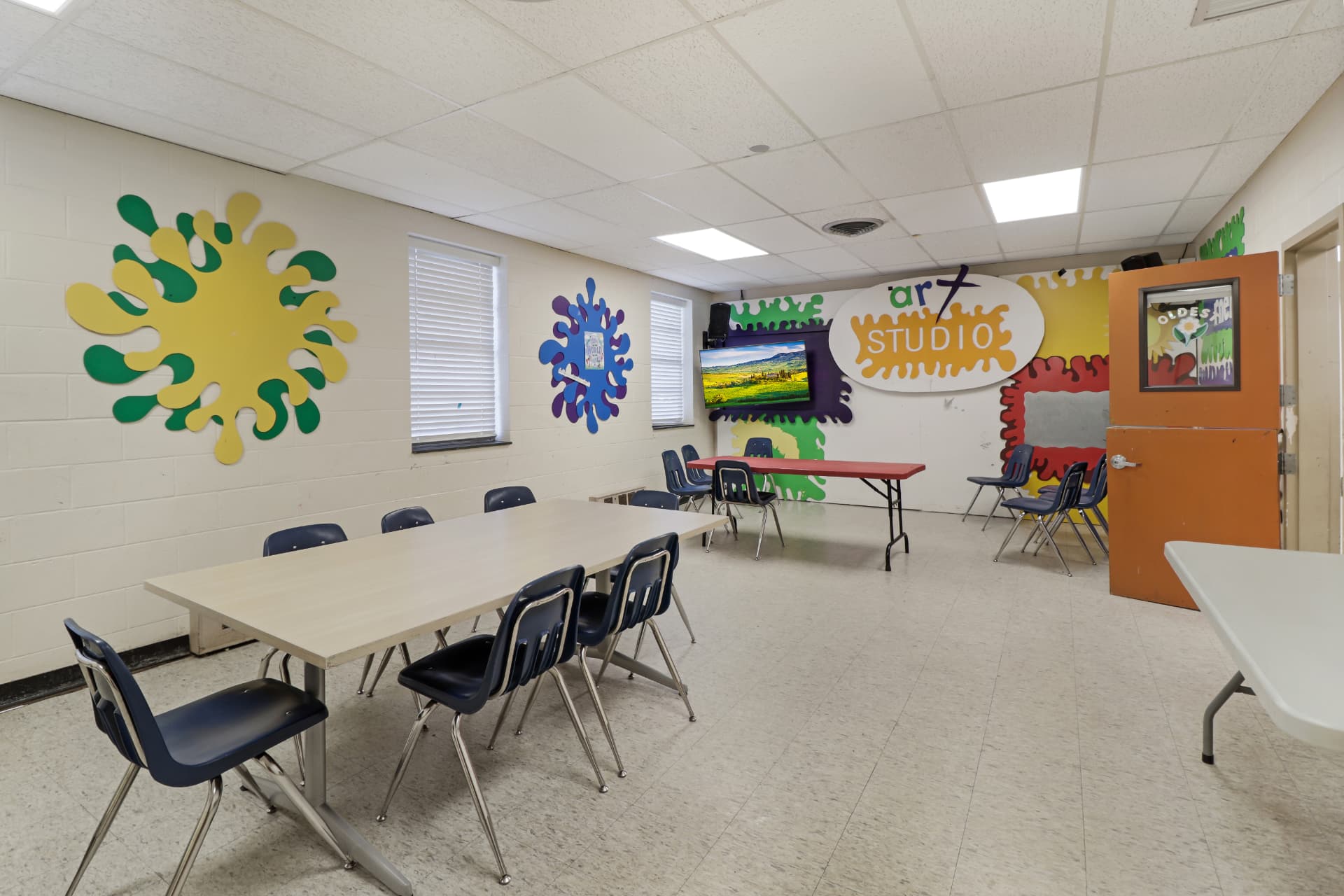 Children's art studio classroom with tables and murals